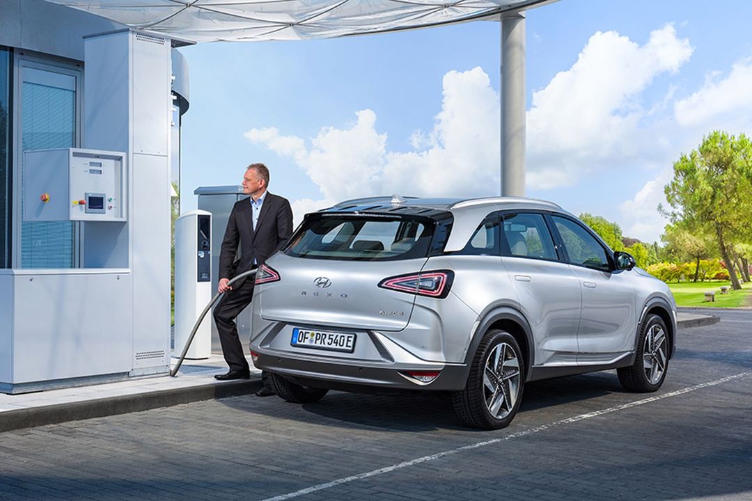 Ein Businessmann betankt einen Hyundai mit Wasserstoff an einer Wasserstofftankstelle